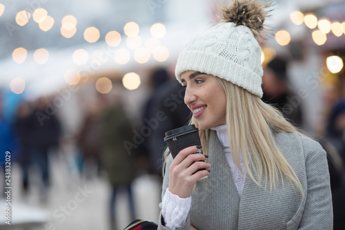 Beautiful winter girl drinking coffee outdoor, attractive young woman with cocoa cup under snow, winter woman outdoors portrait, girl in winter clothes.