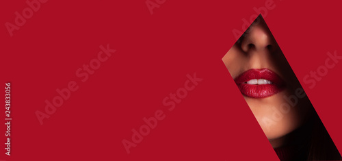 Girl with bright make up  red lipstick looking through hole in red paper. Make up artist  beauty concept. Ready to party. Cosmetics sale. Beauty salon advertising banner with copy space