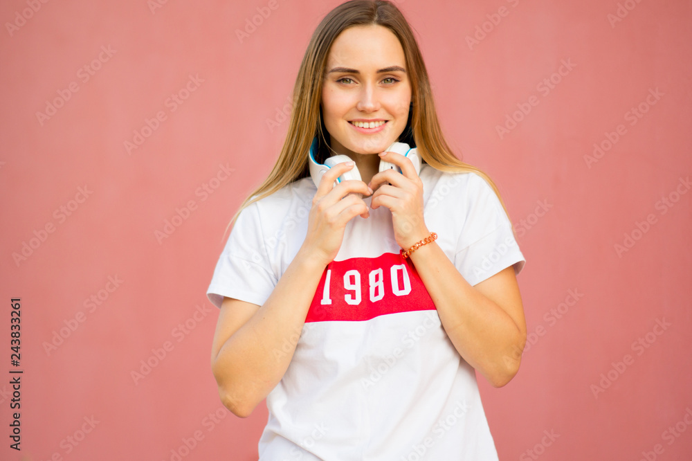 Beautiful .happy girl with headphones in casual white t-shirt, casual clothes style on pink background. Portrait of pretty young woman