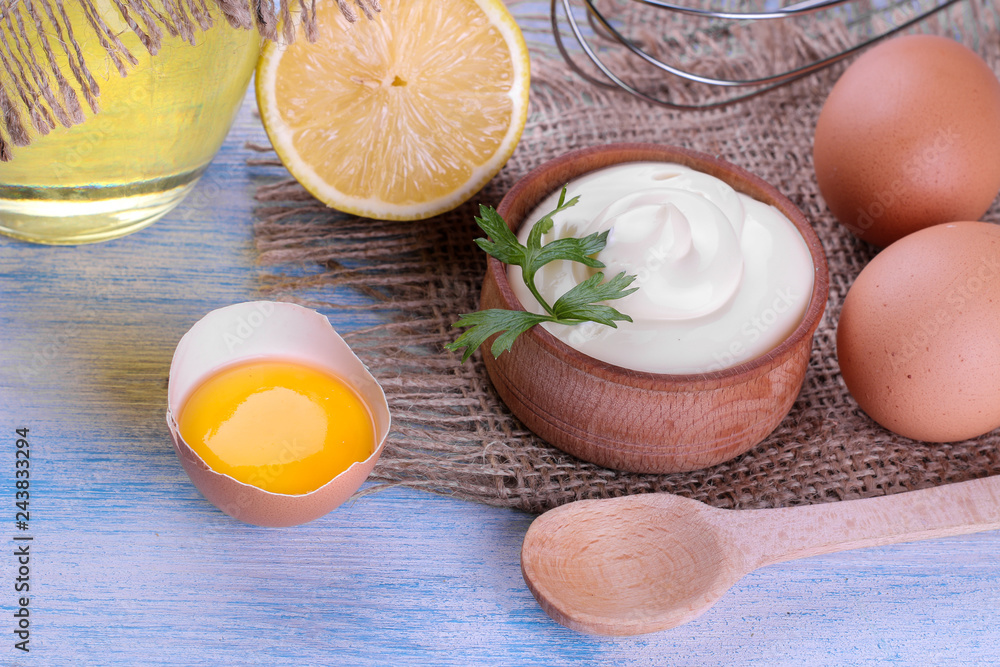 Mayonnaise in a wooden bowl and ingredients for making mayonnaise on a blue wooden background. white sauce. Mayonnaise in a wooden bowl and ingredients for making mayonnaise on a blue wooden background. white sauce.