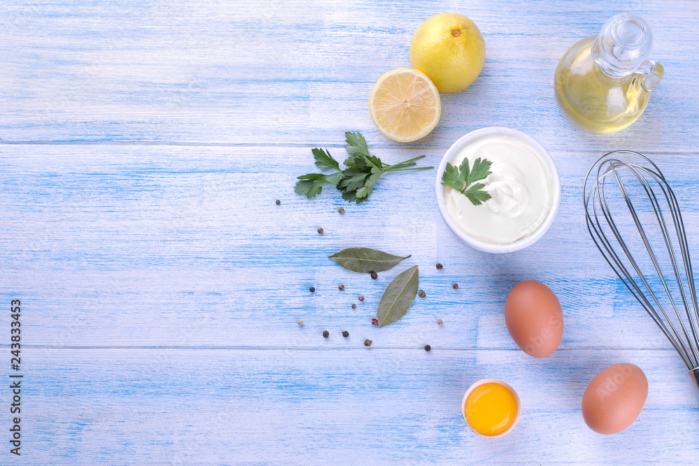 Mayonnaise in a white bowl and ingredients for making mayonnaise on a blue wooden background. white sauce. with space for text. view from above Mayonnaise in a white bowl and ingredients for making mayonnaise on a blue wooden background. white sauce. with space for text. view from above