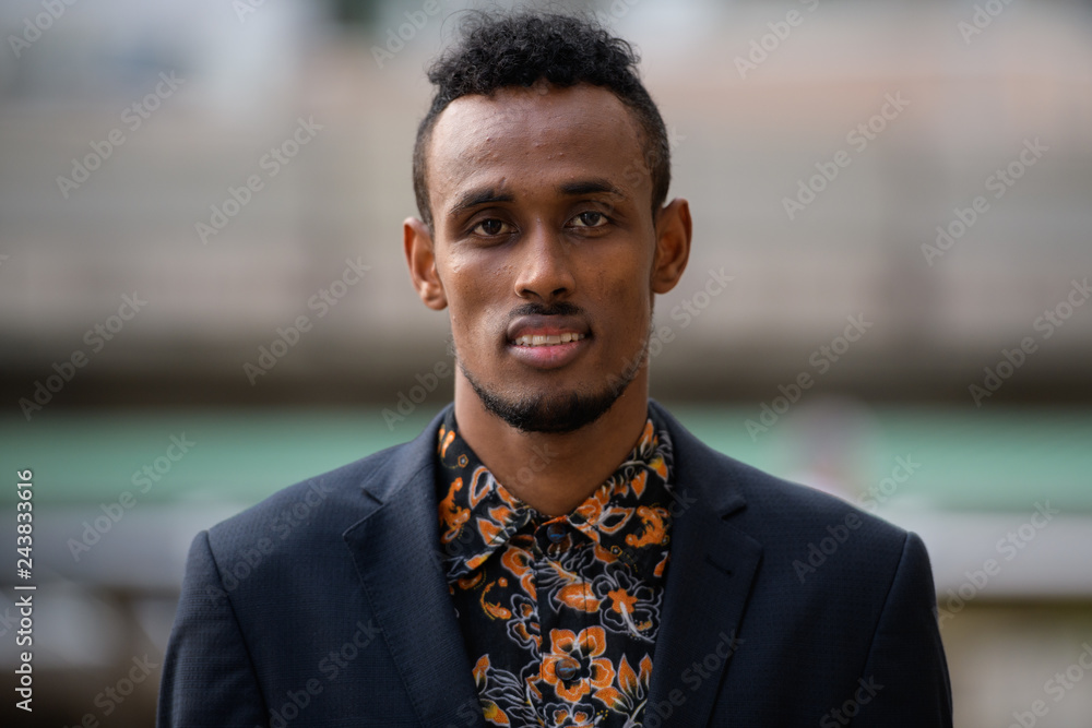 Face of young African businessman looking at camera outdoors Face of young African businessman looking at camera outdoors