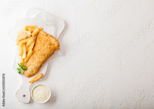 Photography Traditional British Fish and Chips with tartar sauce on chopping board on white stone table background