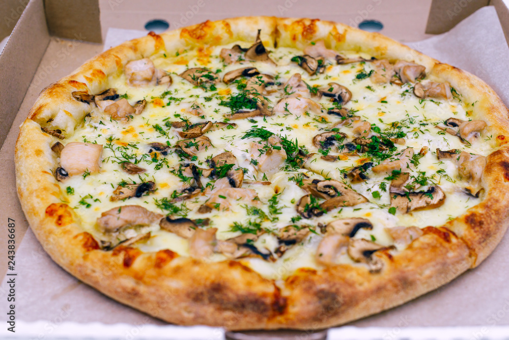 Pizza in a cardboard box on a light background. Top view. Pizza delivery. Pizza menu. Pizza on the kitchen table.