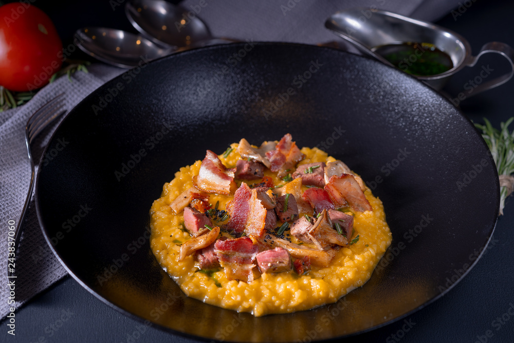 Risotto with saffron, veal and mushrooms on a black plate Risotto with saffron, veal and mushrooms on a black plate