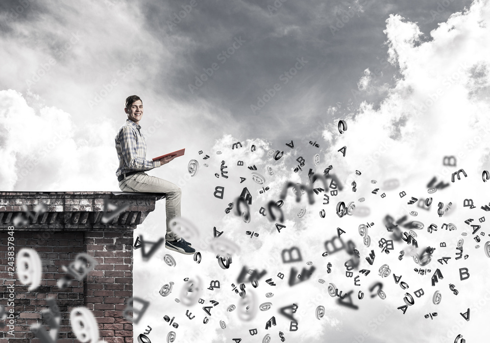 Man on roof edge reading book and symbols flying around Man on roof edge reading book and symbols flying around