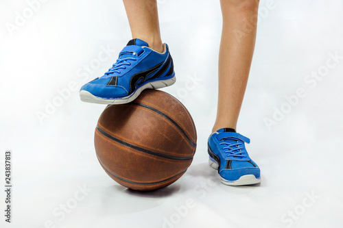 Boy - teenager - basketball player put his foot in a blue sneaker on a basketball