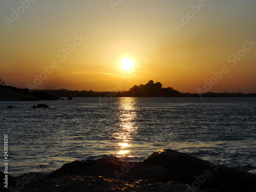 Sunset on a river ocean lake with a ray of sunlight reflecting on the water during the golden hour