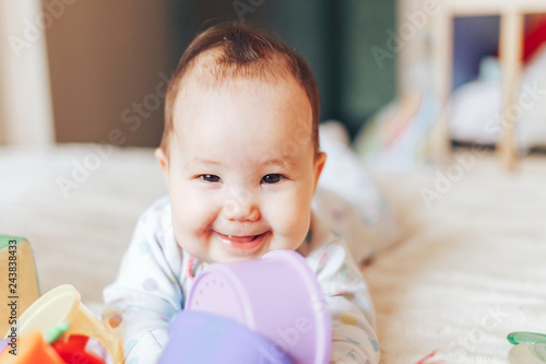 Portrait of smiling happy baby girl playing with toy on bed at home