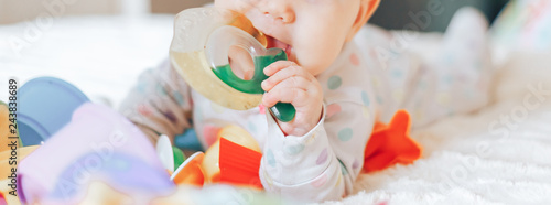 Foto Portrait of a cute 6 month old baby, boy or girl, playing with a teething toy