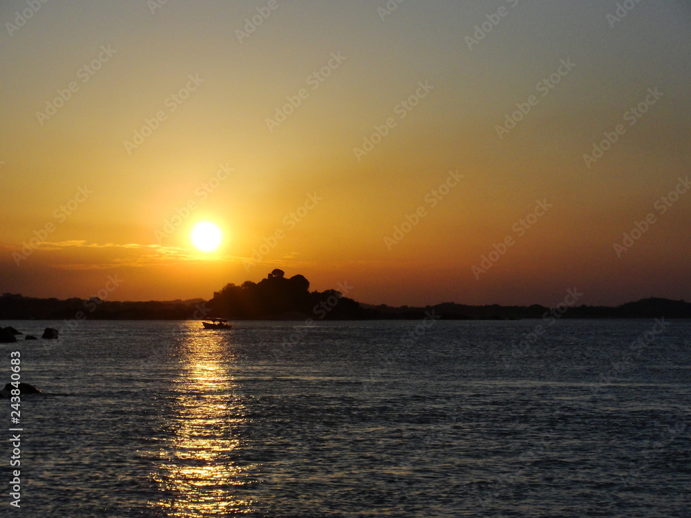 Sunset in a river ocean with a boat passing right through the sunlight