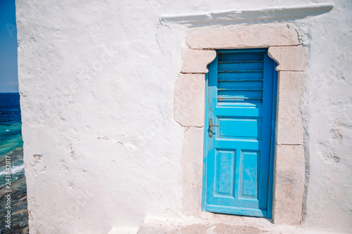 Traditional houses withe blue doors in the narrow streets of Mykonos, Greece. © travnikovstudio