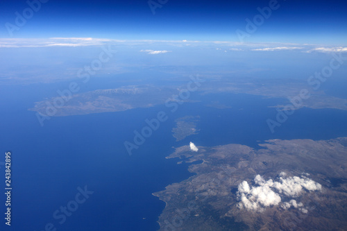 View from a flying plane in the sky to the islands in the ocean through the clouds