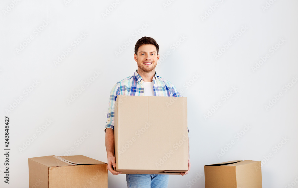 moving, people and real estate concept - happy man holding cardboard box at new home moving, people and real estate concept - happy man holding cardboard box at new home