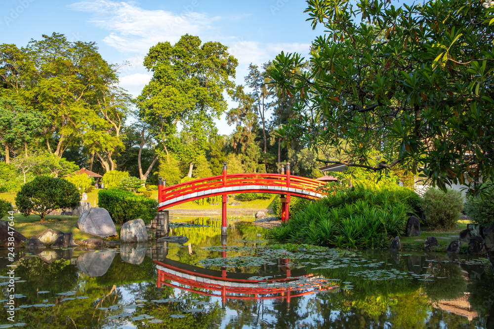Red bridge over a still lake in a garden