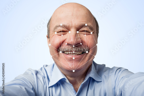 Elderly man holding a smartphone passing through facial recognition.