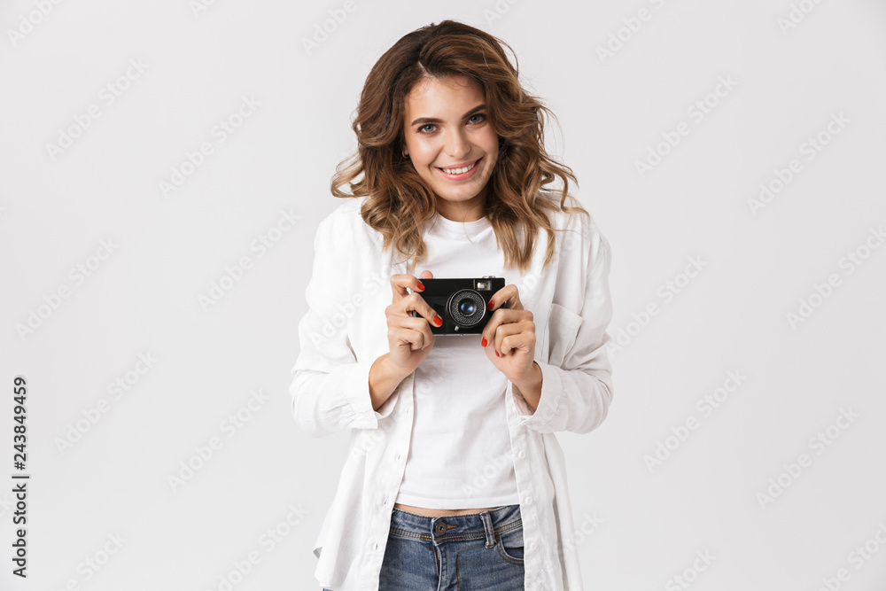 Portrait of positive woman in casual clothes holding retro camera while standing, isolated over white background Portrait of positive woman in casual clothes holding retro camera while standing, isolated over white background