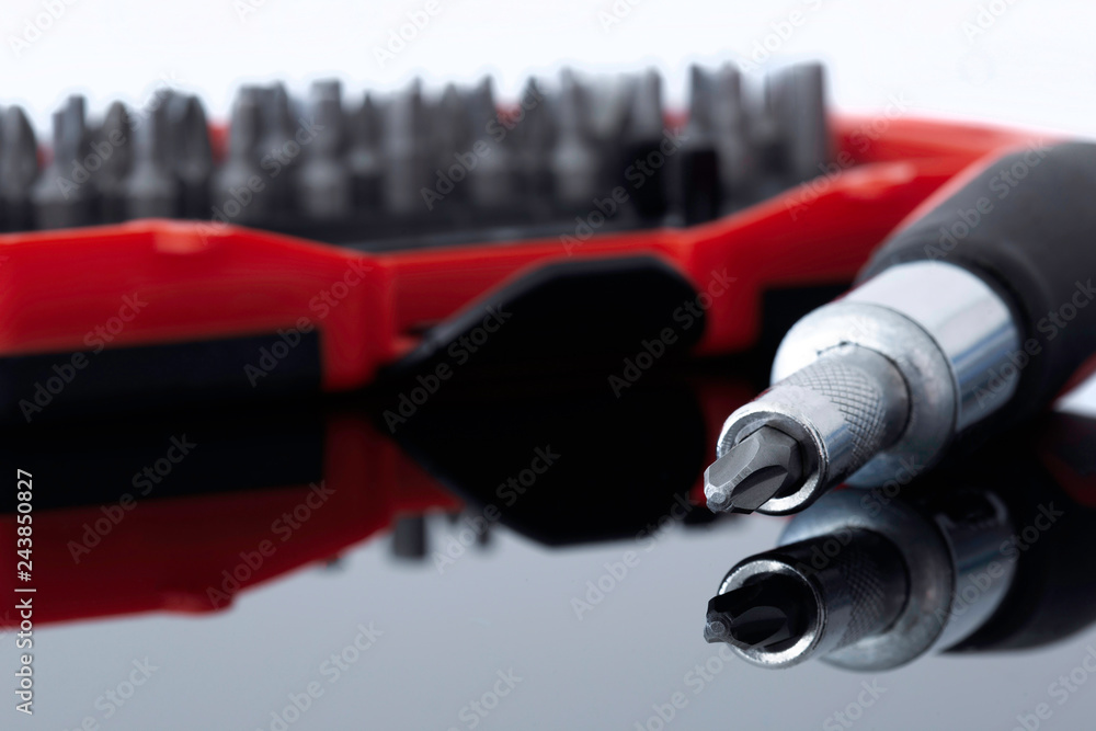 Fototapeta premium Screwdriver with phillips head with various bits in a case in the background reflected on a glass surface