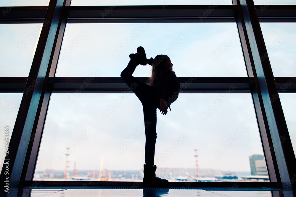 Fototapeta premium Little girl in airport near big window while wait for boarding