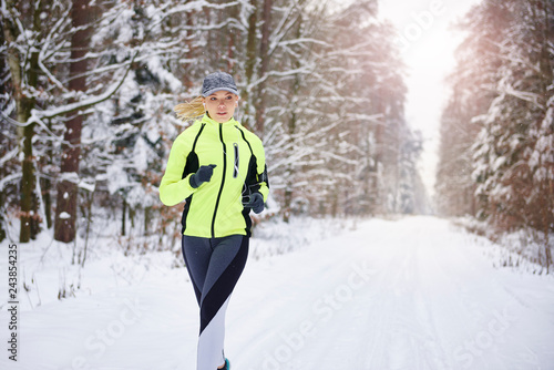 Front view of woman running in winter forest © gpointstudio