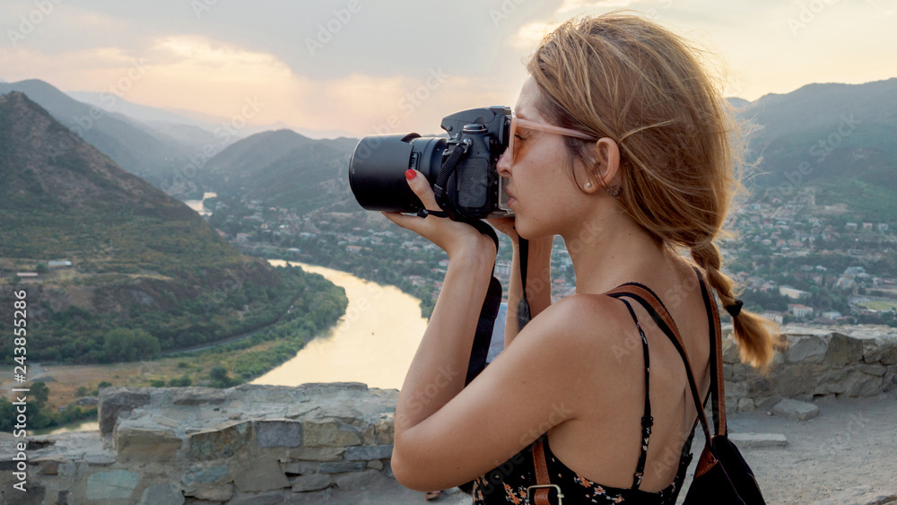 Female photographer, taking pictures of mountain landscape at sunset - obrazy, fototapety, plakaty 