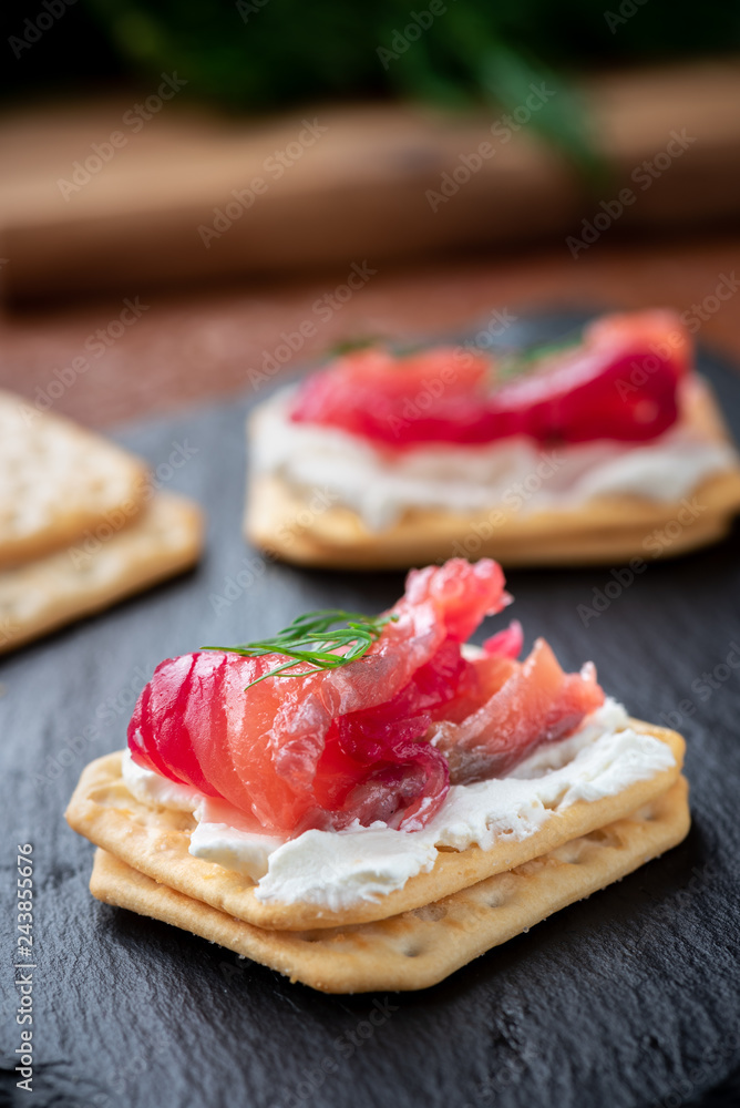 Appetizer cracker with salmon on a black board. Gravlax Appetizer cracker with salmon on a black board. Gravlax