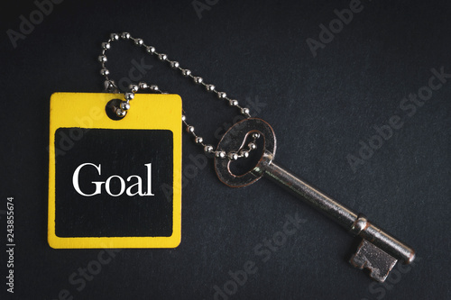 GOAL inscription written on wooden tag and key on black background with selective focus and crop fragment. Business and education concept