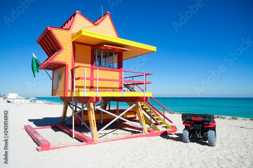 Empty view of a colorful lifeguard tower standing with a green flag on Miami Beach on a bright calm summer morning