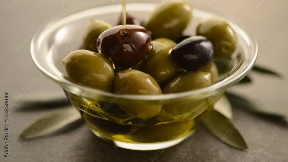 Organic olive oil. Bottle of Extra virgin oil pouring in to glass bowl with olives. Organic olive oil. Bottle of Extra virgin oil pouring in to glass bowl with olives.