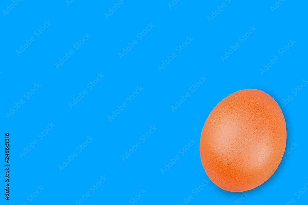 Fototapeta premium Single raw brown egg on blue background with copy space for your text
