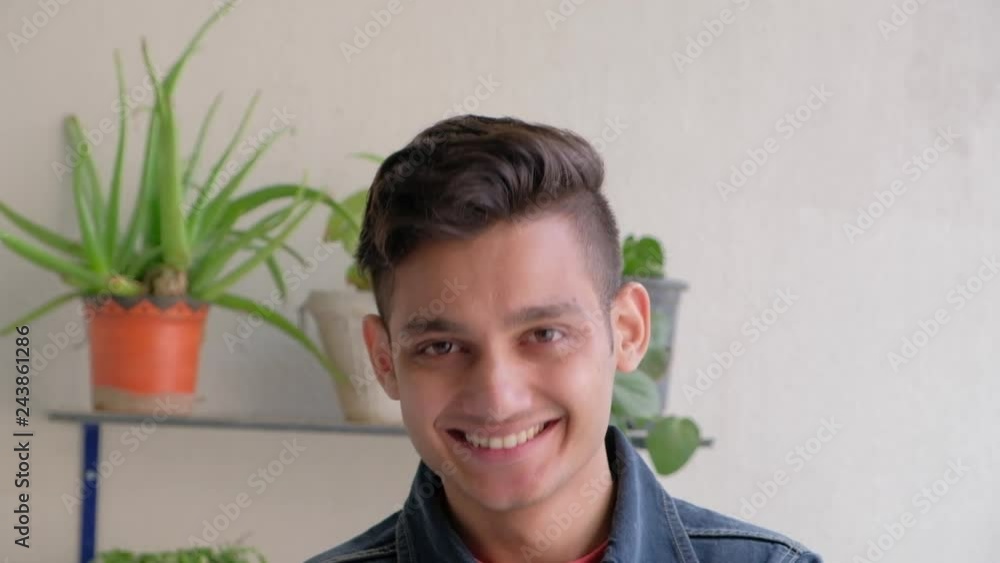 Young man looks at the camera and smiles and laughs with his tooth showing happy and elated 