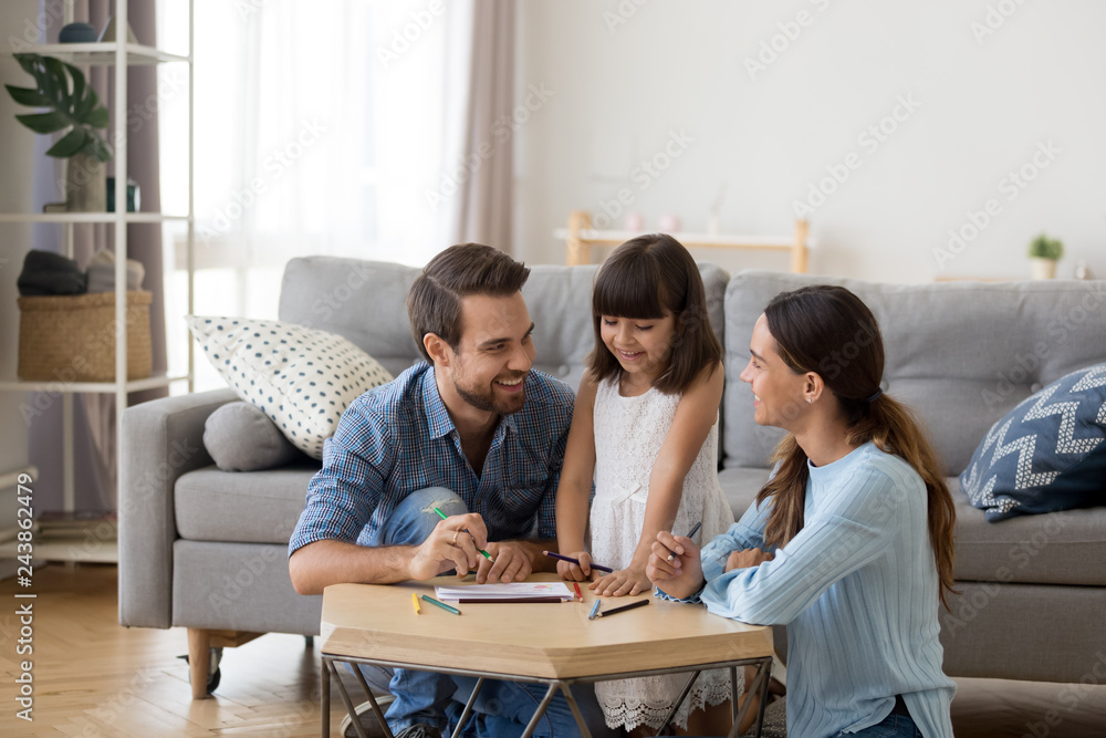 Happy family with kid playing together, caring mom and dad smiling teaching little daughter to draw with color pencils, mother and father having fun with cute child help in creative weekend activity Happy family with kid playing together, caring mom and dad smiling teaching little daughter to draw with color pencils, mother and father having fun with cute child help in creative weekend activity