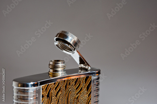 Metal flask for alcoholic drinks closeup shot on gray background photo