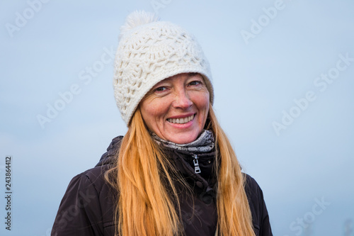 Happy smiling mature woman, with beautiful long hair, wearing white knitted hat, walks along the edge of the salt Sakskoe lake. Saki, Crimea. © Alexander