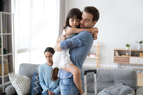 Sad little girl upset by father leaving embracing dad, depressed child saying goodbye hugging daddy going away, kid and parents divorcing breaking up, family separation, shared custody concept