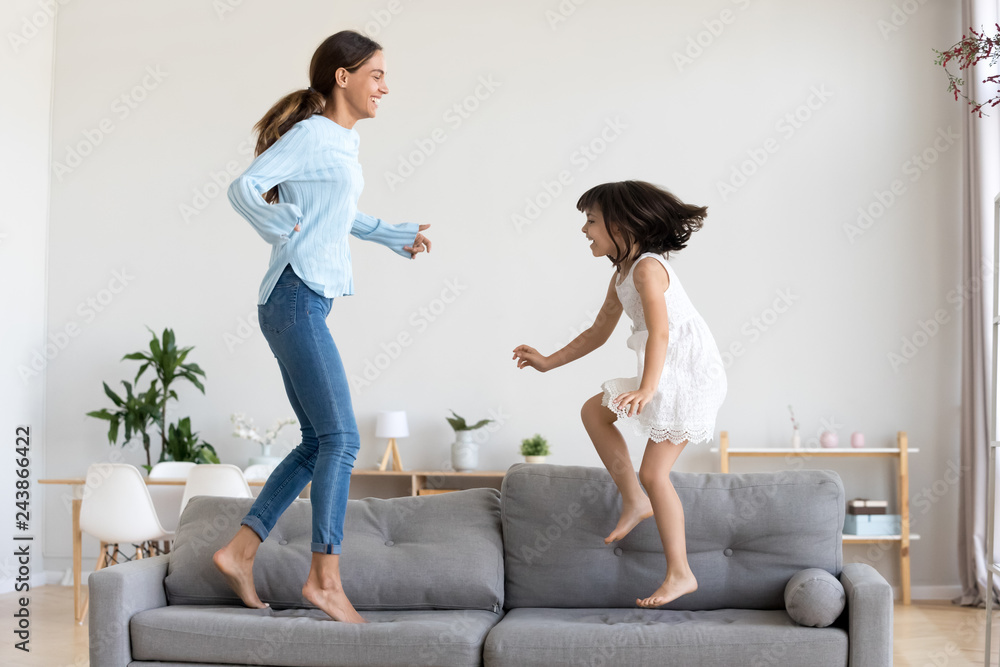 Family, video game and online gaming on home sofa with a pregnant mother  and daughter on a living room couch together while happy and having fun.  Woman and girl kid together for