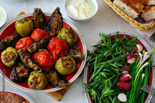 Azerbaijani dolma with eggplant, tomato and pepper, yogurt, greenery and bread on the table