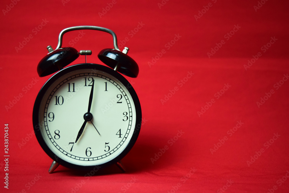 Clock ticking to 7 o'clock on the red background Clock ticking to 7 o'clock on the red background