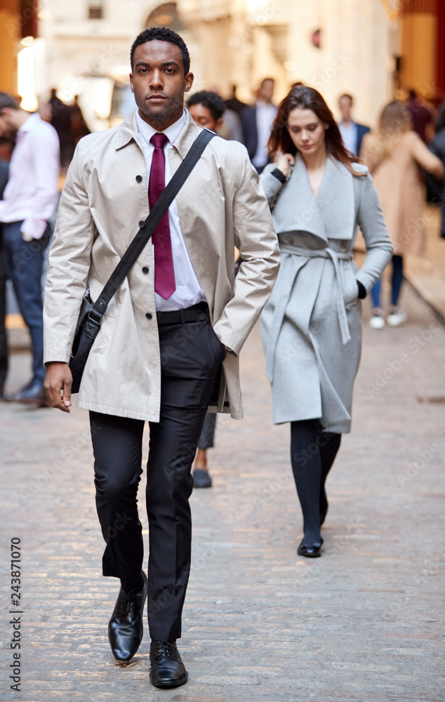 Millennial black businessman walking in a city street looking to camera, full length Millennial black businessman walking in a city street looking to camera, full length