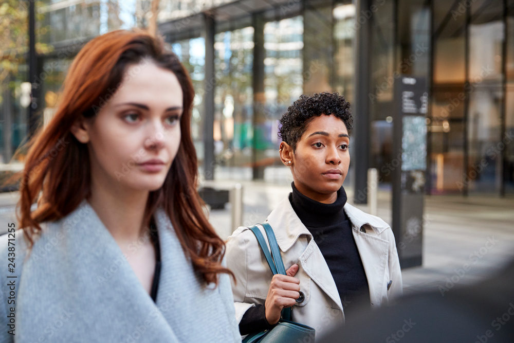 Two young adult businesswomen walking in the city of London, close up, selective focus