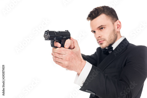 handsome serious killer in black suit aiming with handgun, isolated on white