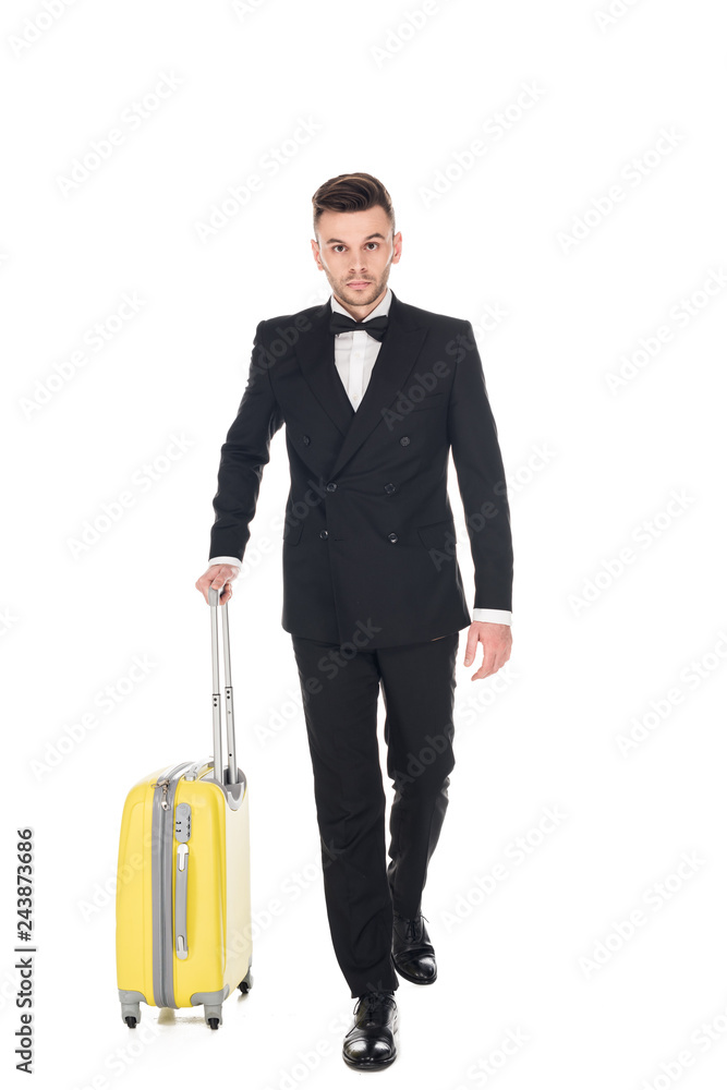 handsome tourist in black tuxedo walking with suitcase isolated on white handsome tourist in black tuxedo walking with suitcase isolated on white