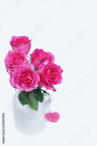 Lovely pinky blossom rose in vase on wooden table with white wall background, sweet gift concept