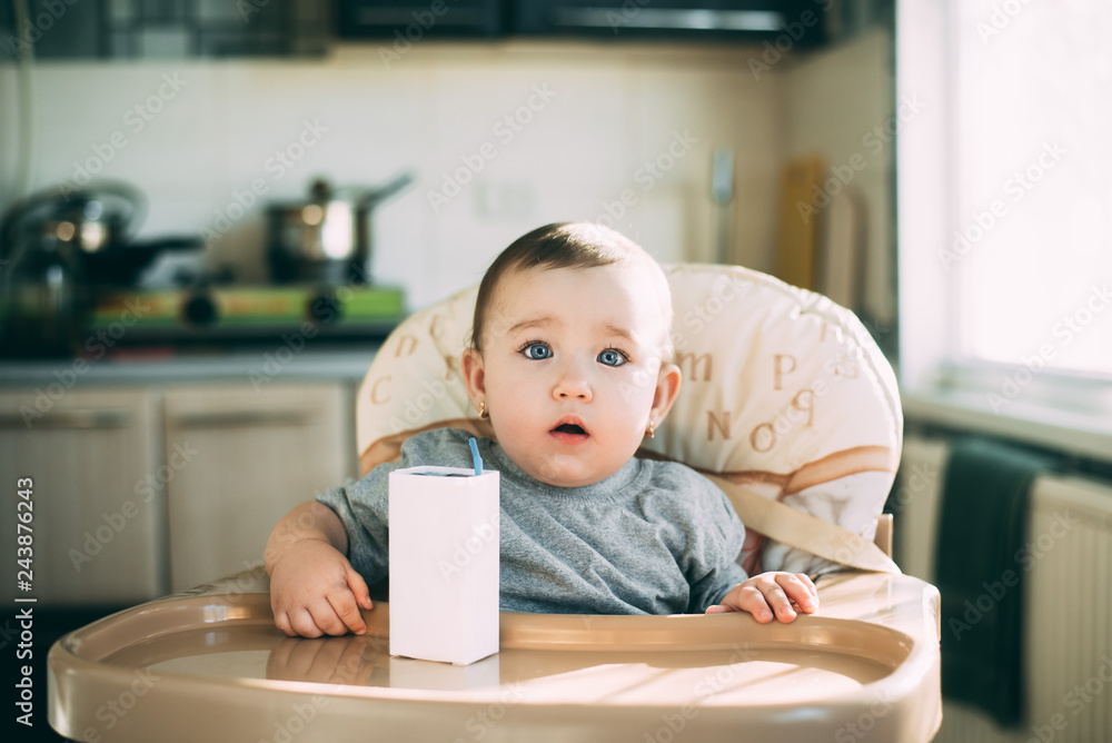 A child, a girl drinking juice or milk with a tube of white packaging there is a place for the inscription A child, a girl drinking juice or milk with a tube of white packaging there is a place for the inscription