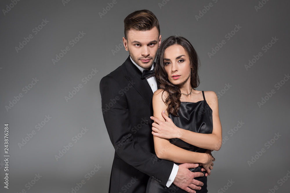 handsome boyfriend hugging beautiful elegant girl isolated on grey handsome boyfriend hugging beautiful elegant girl isolated on grey