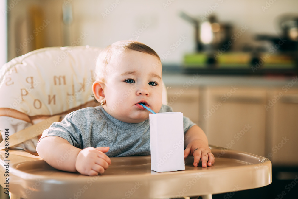 A child, a girl drinking juice or milk with a tube of white packaging there is a place for the inscription A child, a girl drinking juice or milk with a tube of white packaging there is a place for the inscription