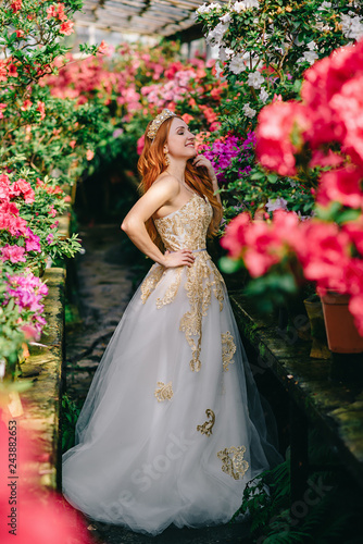 young woman in luxurious dress standing in flowered garden
