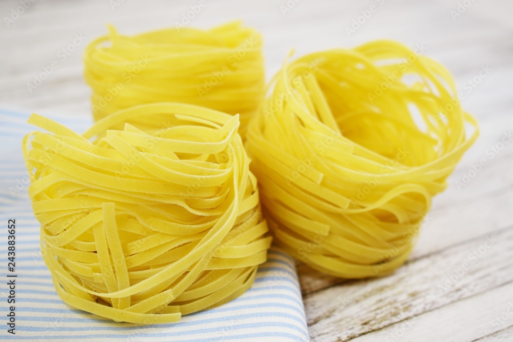 Pasta in the shape of a nest on a wooden background.