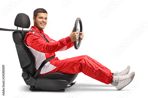 Male racer in a car seat holding a steering wheel and smiling at the camera