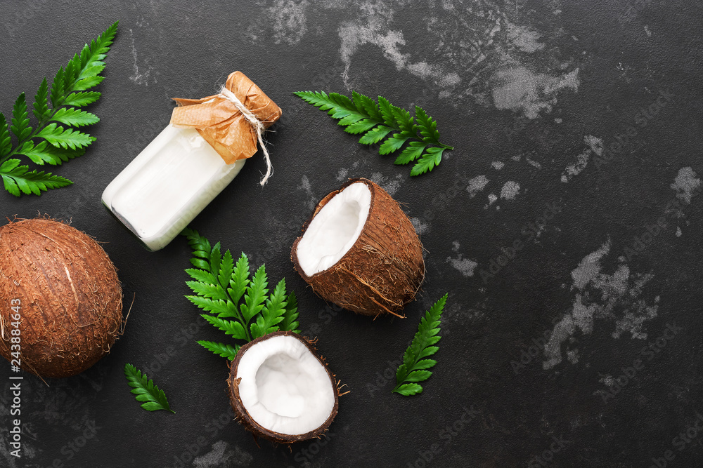 Coconut and milk in a bottle decorated with fern leaves on a black stone background. Top view, flat lay,copy space Coconut and milk in a bottle decorated with fern leaves on a black stone background. Top view, flat lay,copy space